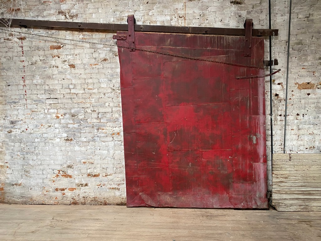 Closed red fire door with whitewashed wall